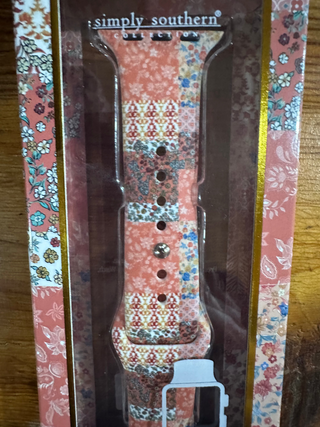 A floral patterned watch band in its retail packaging, featuring a coral pink, red, and blue paisley and geometric design. The brand name 'simply southern' is visible on the left side of the box.